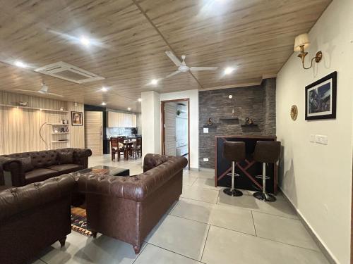 a living room with leather couches and a bar at Velvet Hills Barog in Barog
