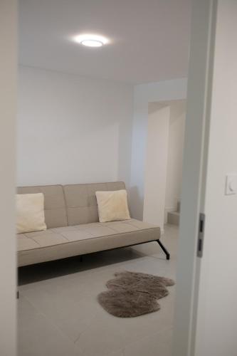 a white living room with a couch and a rug at Appartement Nova in Saint-Louis
