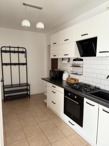a kitchen with white cabinets and a black stove top oven at Dom Gościnny Ania, Apartament nr 3 in Wisełka