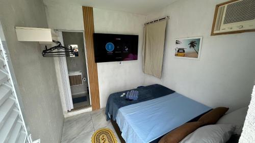 a small bedroom with a bed and a television at Pousada Aconchego de Maricá in Maricá