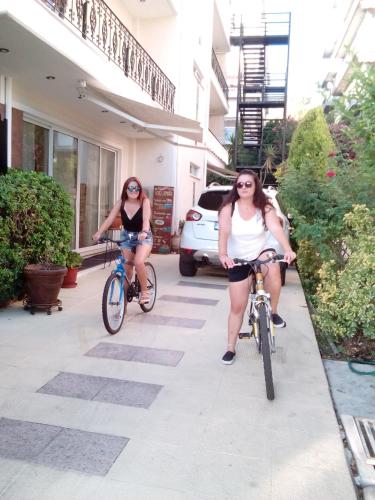 two women riding bikes down a sidewalk at Hotel Romantica in Loutra Edipsou