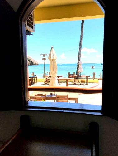 a window view of a beach with an umbrella at Morro Beach Hotel in Morro de São Paulo