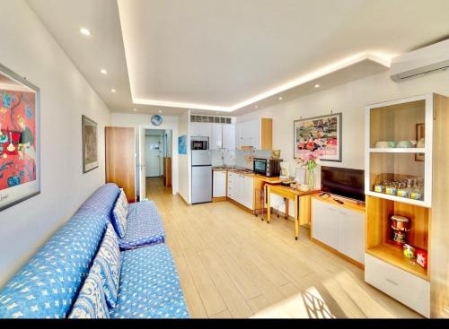 un salon avec un canapé bleu et une cuisine dans l'établissement Le Berkeley Bilocale fronte mare-Free Parking-Riscaldamento, à Menton