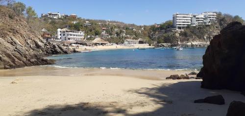 a beach with buildings in the background and a beach with boats at Angelita's Nest House in Puerto Ángel