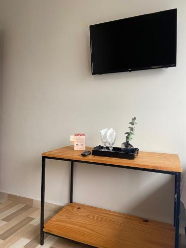 a table with a flat screen tv on a wall at Hotel Carmelita in Aparecida