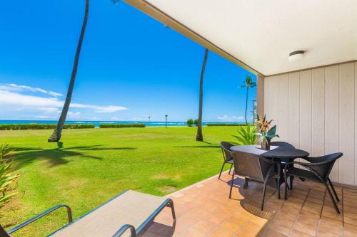 a patio with a table and chairs and a field of grass at Condos in Kapaa in Kapaa