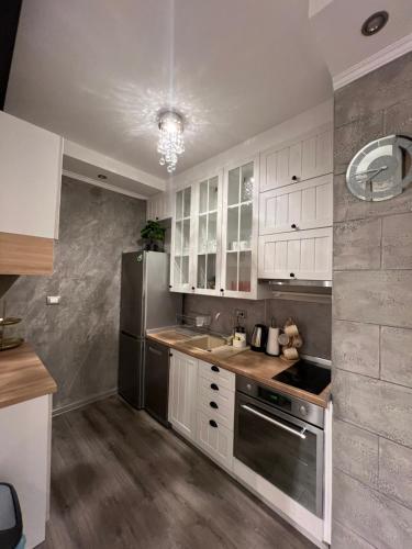 a kitchen with white cabinets and a stainless steel refrigerator at Apartman M&A in Inđija