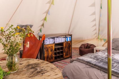 a room with a table and a tent at Hill Top Hideaway Shepherds Hut with Hot Tub in Woodham Mortimer