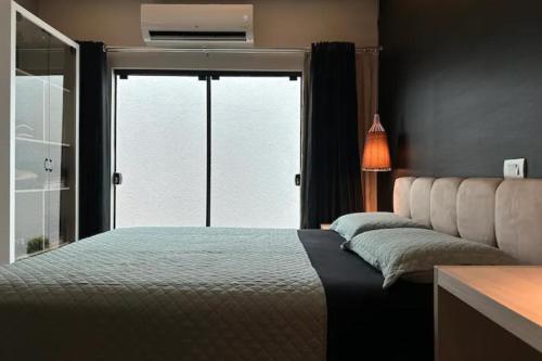 a bedroom with a bed and a large window at Casa Charmosa Próxima a Avenida das Cataratas in Foz do Iguaçu