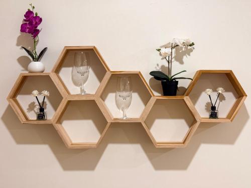 a shelf with three glass wine glasses and flowers at Serenova Hotel Siam Paragon, Bangkok in Bangkok