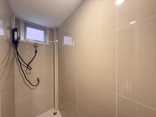 a bathroom with a shower with a phone on the wall at Serenova Hotel Siam Paragon, Bangkok in Bangkok