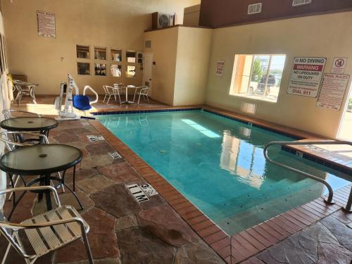 a large swimming pool with tables and chairs in a room at Best Western PLUS Rockwall Inn & Suites in Rockwall