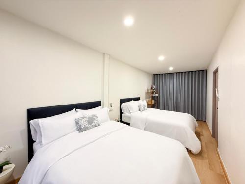 two white beds in a room with white walls at Serenova Hotel Siam Paragon, Bangkok in Bangkok