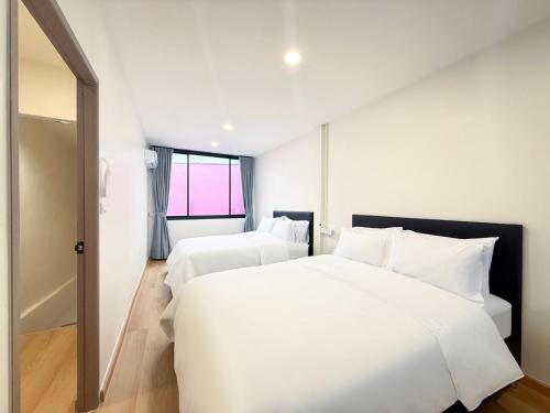 a white bedroom with two beds and a window at Serenova Hotel Siam Paragon, Bangkok in Bangkok