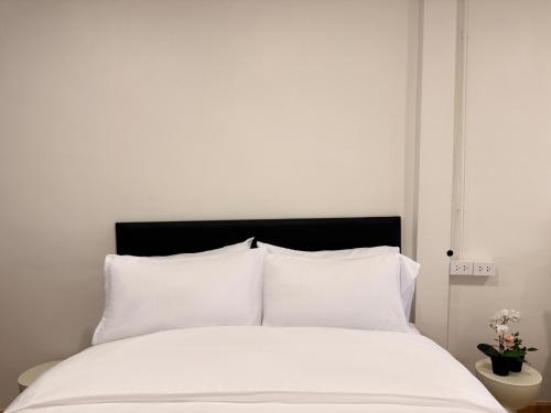 a white bed with white sheets and a black headboard at Serenova Hotel Siam Paragon, Bangkok in Bangkok