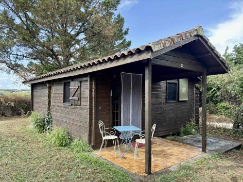 a small cabin with a table and chairs on a deck at Camping le Cabri in Duras