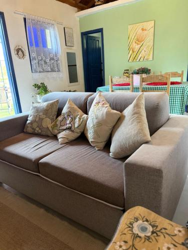a couch with many pillows on it in a living room at VILA ACONCHEGO AZUL- casa 1 in Aracê