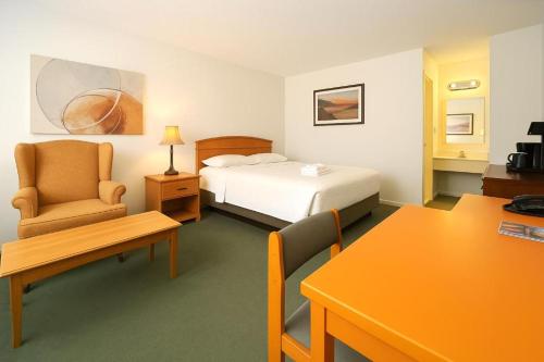 a hotel room with a bed and a chair and a table at Midtown Premium in Saskatoon