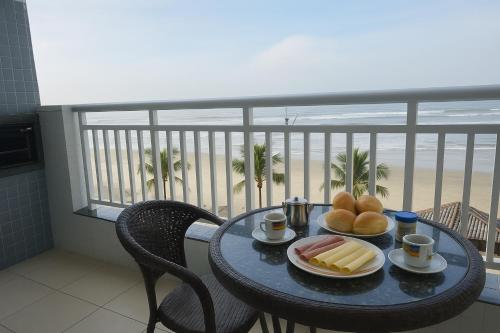 a table with food on a balcony with a view of the beach at Refúgio do Aconchego Frente Praia Ocean Club in Mongaguá