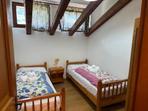 two twin beds in a room with two windows at Mansarda Mulaz in Falcade