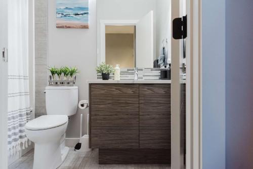 a bathroom with a toilet and a sink with a mirror at NordicSauna 3 Ensuite baths TheYellowDoorRetreat in Edmonton