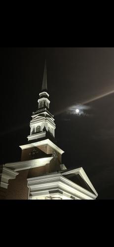 a tall white steeple of a building with a clock at Boone Trace Inn Room 2 in Pineville