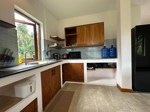 a kitchen with wooden cabinets and a sink and a window at Ploythai Villa Koh Phangan in Haad Pleayleam