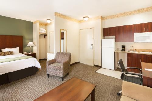 a hotel room with a bed and a kitchen at Hawthorn Suites by Wyndham Rancho Cordova/Folsom in Rancho Cordova