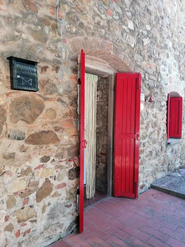 a red door on a stone building with a sign at Casa Belvedere in Suvereto