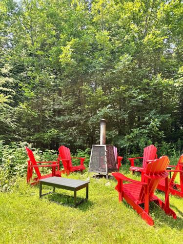 a group of red chairs and a table in the grass at Cottage 61 des Cervidés in Eastman