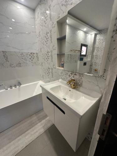 a white bathroom with a sink and a bath tub at Chambre Cosy à Dakar in Dakar