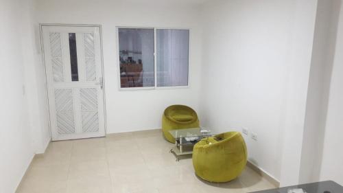 two yellow chairs in a white room with a door at Los primos 2 in Santa Marta