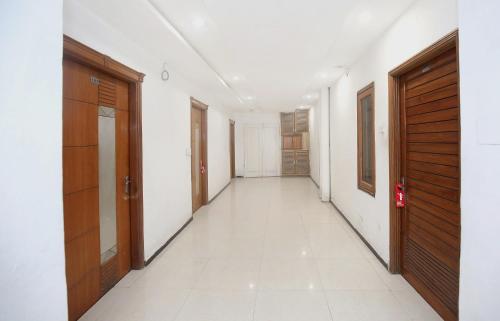 an empty hallway with wooden doors and white tiles at Super Hotel O Queensland in Amritsar