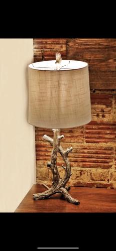 a lamp sitting on a table with a tree branch at Boone Trace Inn Room 7 in Pineville