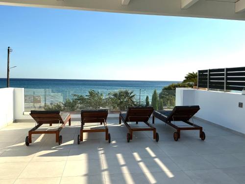 a group of chairs sitting on a patio with the ocean at Fantasea Beachfront Villa in Makry Gialos