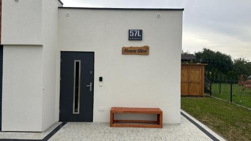 a white building with a door and a wooden bench at Nowa Olza - domek na wynajem in Olza