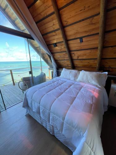 a bedroom with a bed with a view of the ocean at DChalé in Japaratinga
