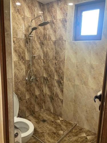 a bathroom with a shower with a toilet and a window at Guest house Dinaya-2 in Dobrinishte