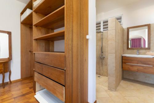 a bathroom with a wooden closet with a sink and a shower at Fare Toamagiti in Paea