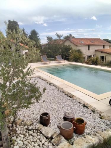 a swimming pool with pots on the ground next to a house at Charming pied-à-terre in Vieux-Ruffec