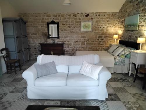 a living room with a white couch and a bed at Charming pied-à-terre in Vieux-Ruffec