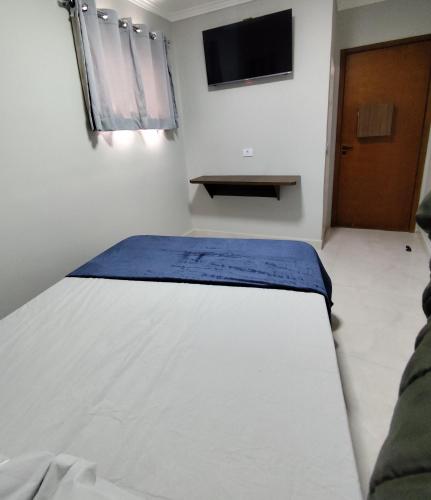 a bed in a room with a tv on the wall at Hotel Mira in Sao Paulo