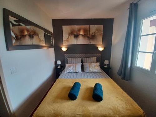 a bedroom with a bed with two blue pillows on it at Chez Anne WIFI dans le logement in Argentat