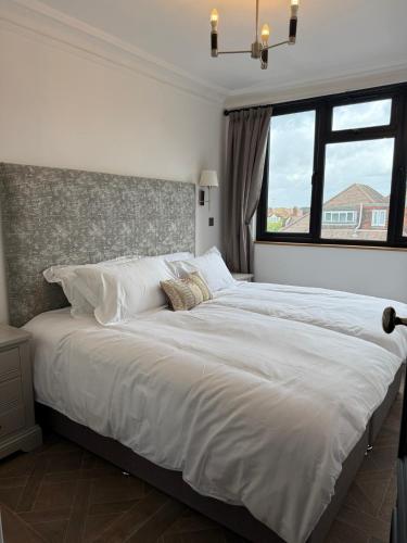 ein großes weißes Bett in einem Schlafzimmer mit Fenster in der Unterkunft The Brent Cross Penthouse in London