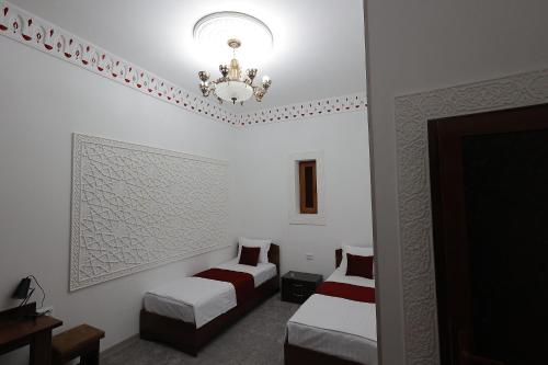 a hotel room with two beds and a chandelier at People Tours Bukhara in Muruntau