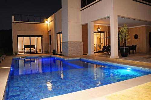 a swimming pool in front of a house at night at Kridarek - Magnifique Villa avec piscine à Marrakech in Douar bel Rhanodour