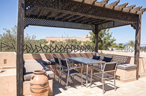a wooden pergola with a table and chairs on a patio at Kridarek - Magnifique Villa avec piscine à Marrakech in Douar bel Rhanodour