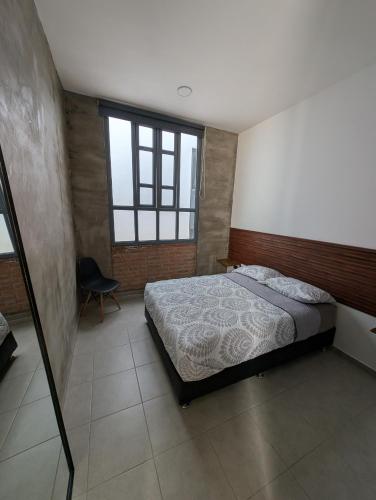 a bedroom with a bed and a chair in it at Departamentos San Marcos in Aguascalientes