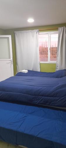 a blue bed in a room with a window at Alojamiento Temporal la Flor in Gobernador Gregores