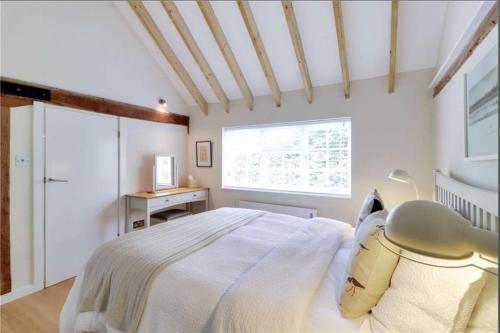 a bedroom with a white bed and a window at Little Puddingcake - Adorable 1 bedroom guesthouse near Chapel Down in Rolvenden